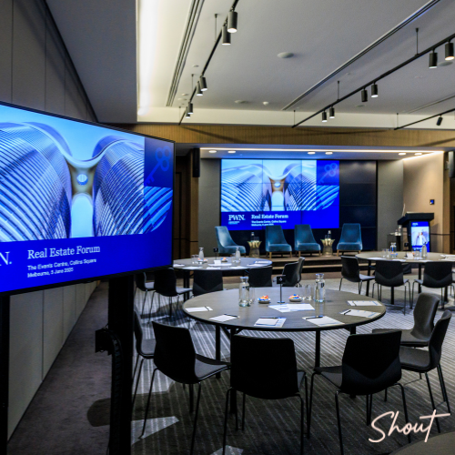 Modern conference room with large screens and round tables.