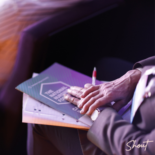 Person holding a Quran with hands clasped together in prayer or reflection.