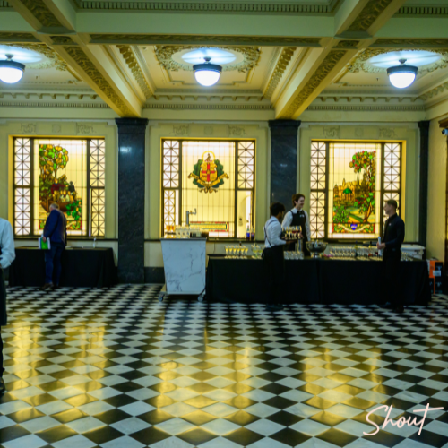 People at a counter in a grand lobby with ornate decor.