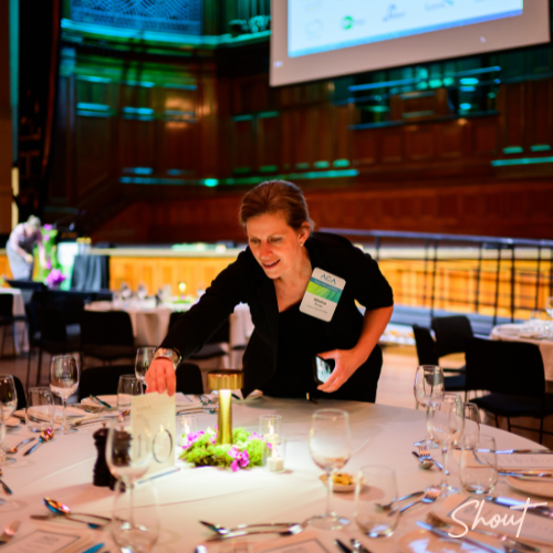 Woman arranging a centerpiece at a banquet table in a formal setting.