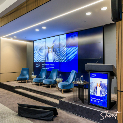 Modern conference room with large digital screens and blue chairs.