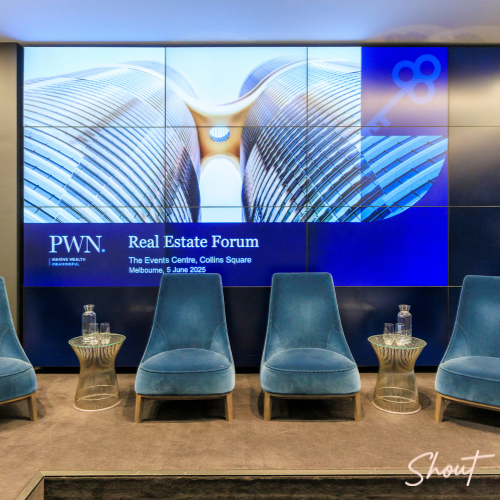 Stage setup for PWN Real Estate Forum with blue chairs and screens.
