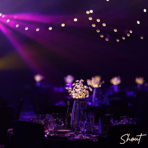 Elegant event setup with purple lighting and floral centerpieces.