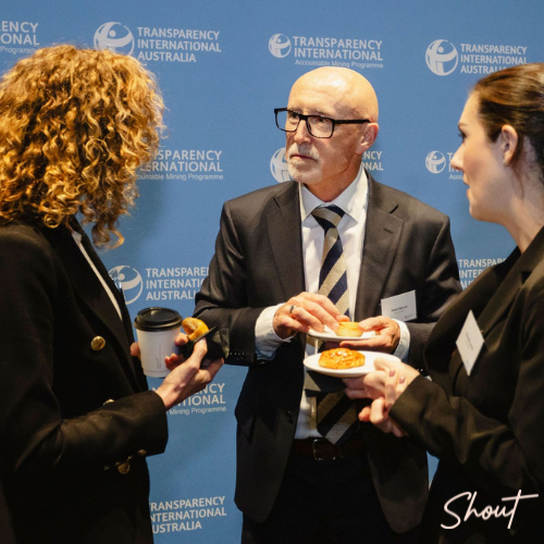 Three professionals engaged in conversation at a formal event.