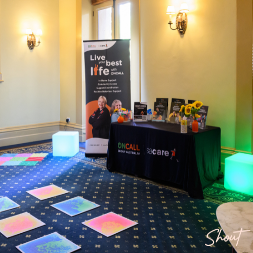 A colorful booth setup with promotional materials and illuminated cubes indoors.
