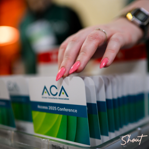 A hand reaches for an ACA conference badge at an event.