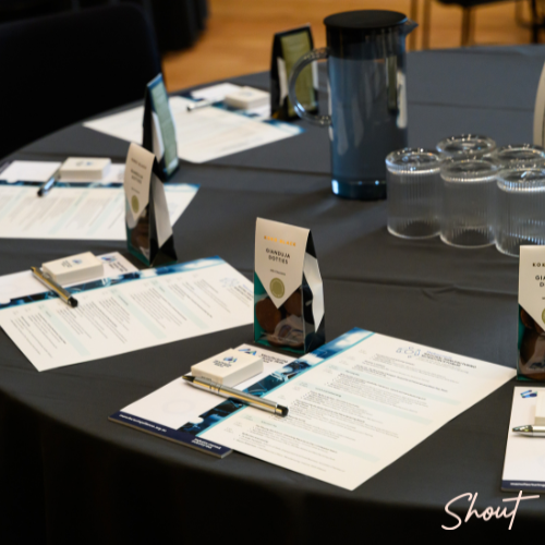 Conference table set with event programs, name cards, pens and refreshments for delegates attending the National Manufacturing Workforce Forum.
