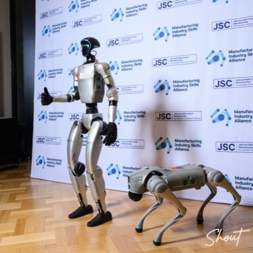 Humanoid robot and robotic quadruped displayed in front of the Manufacturing Industry Skills Alliance media wall at the National Manufacturing Workforce Forum.