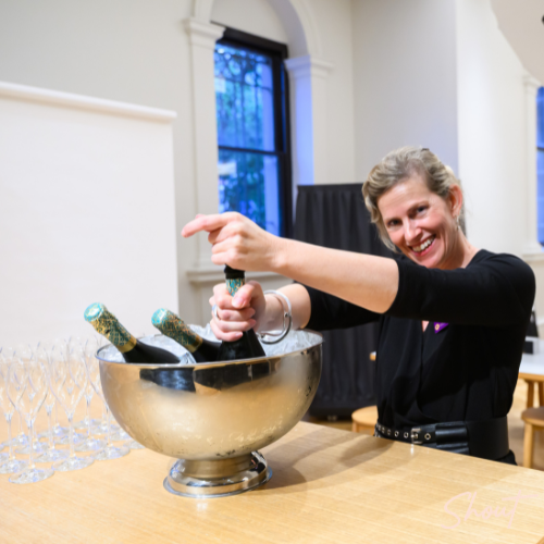 SHOUT Productions team member opening champagne to celebrate a successful National Manufacturing Workforce Forum event.